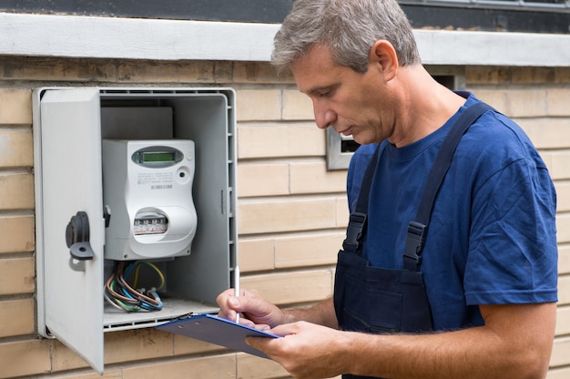 Portrait d'ouvrier électricien inspectant le compteur électrique