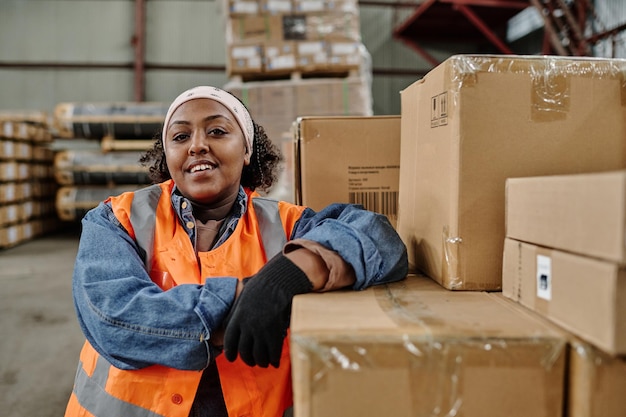 Portrait d'un ouvrier d'entrepôt afro-américain souriant à la caméra alors qu'il travaille dans un entrepôt