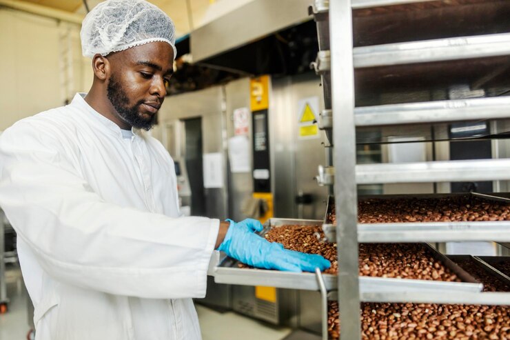 Portrait d'un ouvrier d'une usine alimentaire multiculturelle cuisant des arachides et les préparant pour les biscuits