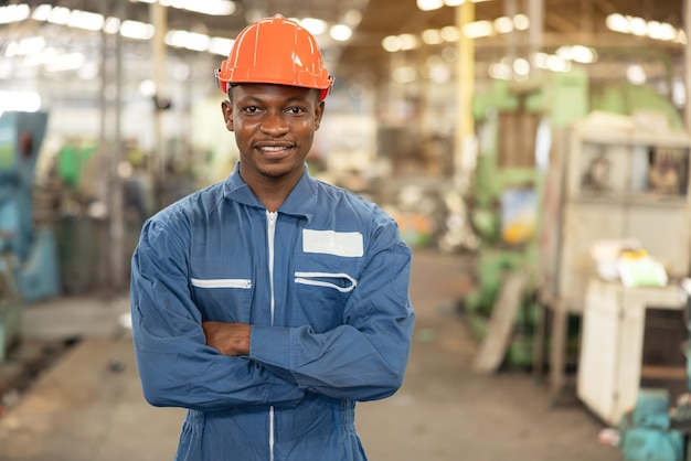 Photo portrait d'un ouvrier d'usine noir dans un casque regardant fixement la photo alors qu'il se tient dans un atelier