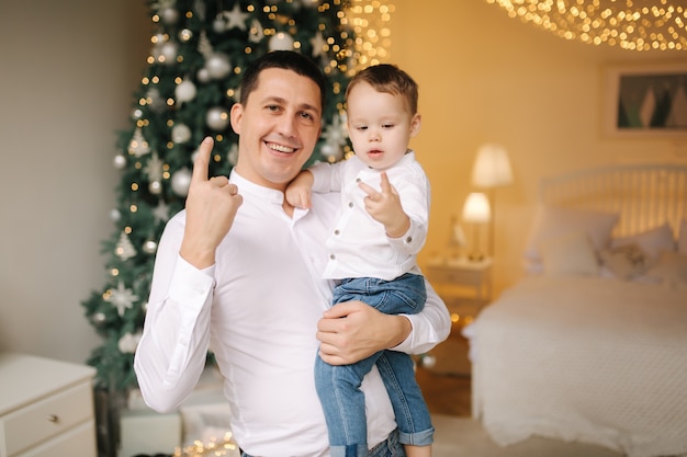 Portrait de papa et fils à la maison près de l'arbre de Noël, tous sourient. Famille de Noël. Bonheur.