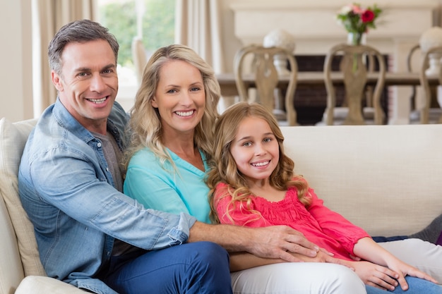 Portrait de parents et fille assise sur un canapé dans le salon