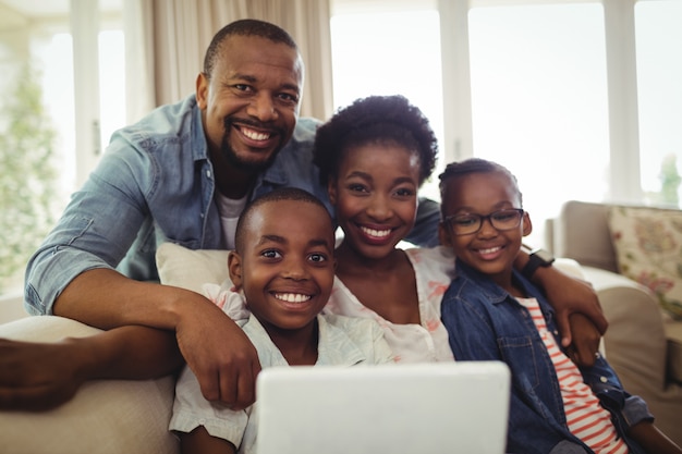 Portrait de parents et fils assis sur un canapé dans le salon