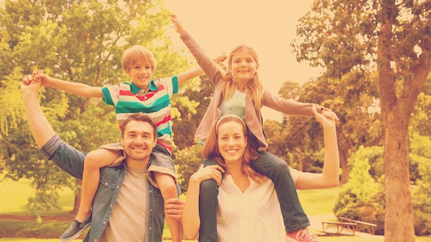 Portrait de parents heureux portant des enfants sur les épaules du parc