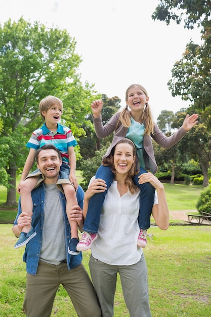 Portrait de parents heureux portant des enfants sur les épaules du parc