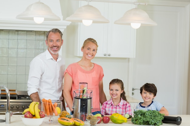 Portrait des parents et de leurs deux enfants debout dans la cuisine