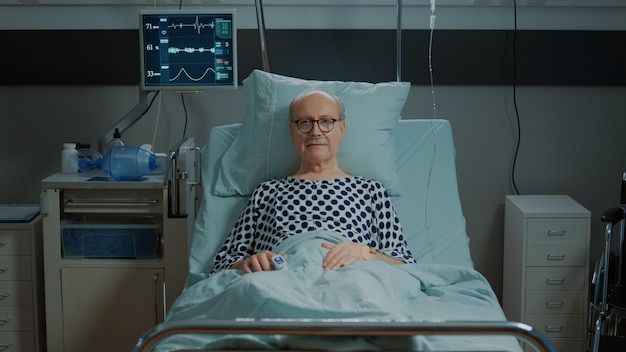 Portrait d'un patient malade restant au lit à l'hôpital avec oxymètre, tube d'oxygène nasal et moniteur. Vieil homme en attente d'un traitement médical pour guérir la maladie, la maladie, la chirurgie de la douleur et les blessures
