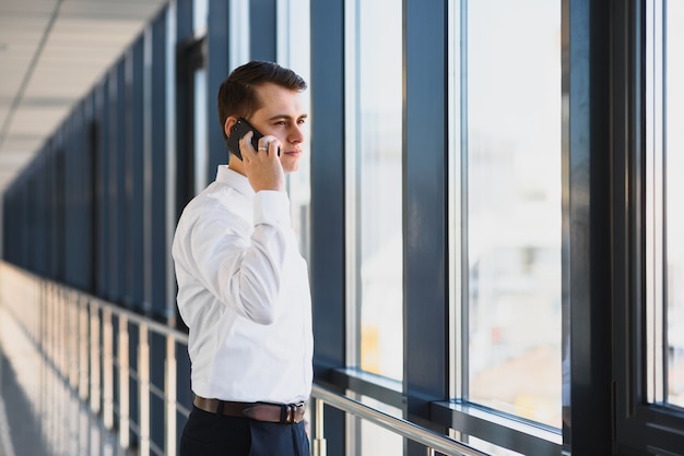 Portrait d'un patron sérieux homme confiant ayant une conversation sur téléphone mobile tout en se reposant après une réunion avec ses partenaires