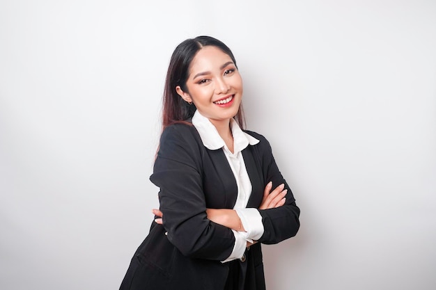 Portrait d'une patronne asiatique souriante et confiante portant un costume noir debout avec les bras croisés et regardant la caméra isolée sur fond blanc