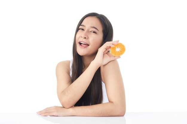 Portrait de peau fraîche parfaite de la belle jeune fille asiatique avec des tranches d'orange à la main isolé sur fond blanc