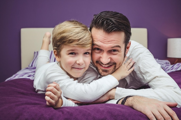 Portrait d'un père et d'un fils allongés sur le lit à la maison