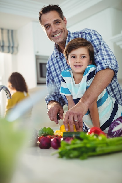 Portrait de père et fils, couper les légumes dans la cuisine