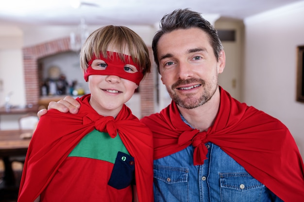 Portrait de père et fils se faisant passer pour un super-héros dans le salon