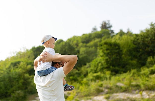 Portrait d'un père heureux donnant à son fils un tour de ferroutage sur ses épaules