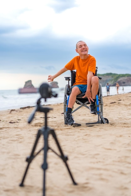 Portrait d'une personne handicapée dans un fauteuil roulant sur la plage en train d'enregistrer une vidéo pour une interview