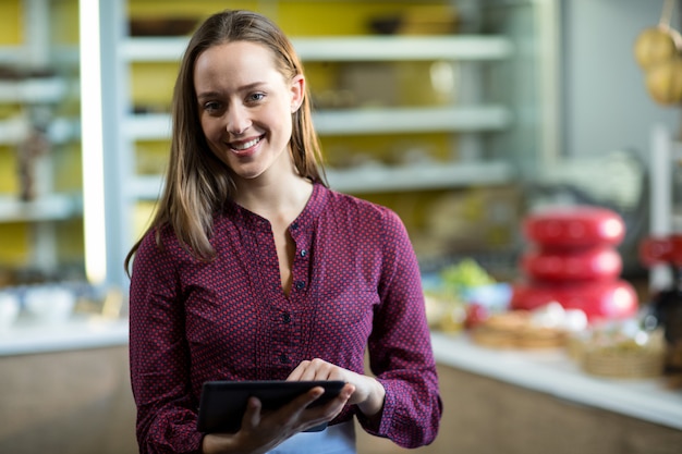 Portrait de personnel féminin souriant à l'aide de tablette numérique au comptoir