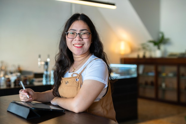 Portrait de personnes indépendantes asiatiques femme d'affaires portant des lunettes élégantes hipste Dessiner ou prendre note sur une tablette numérique avec un stylo électronique pour naviguer sur Internet, discuter et bloguer dans un café