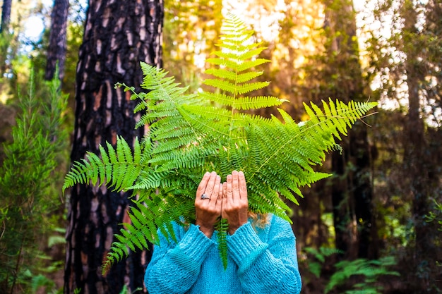 Photo portrait de personnes méconnaissables cachées par de grandes feuilles de la forêt naturelle