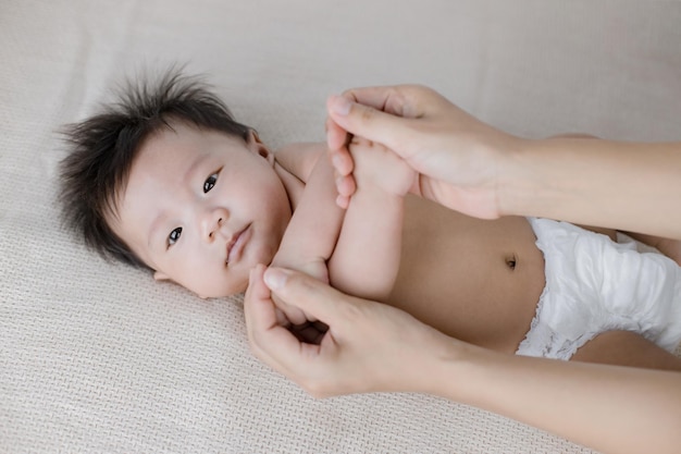 portrait d'un petit bébé curieux allongé sur le lit et maman lui donne un massage des mains.