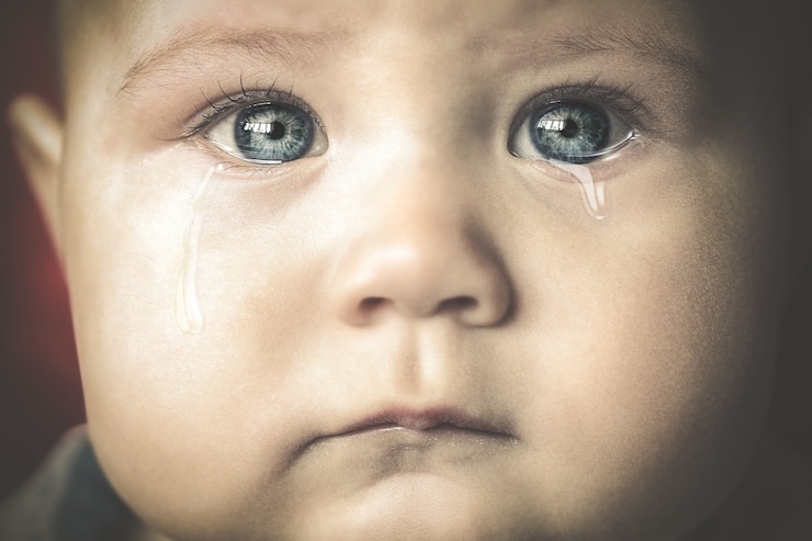 Photo portrait d'un petit bébé qui pleure aux yeux bleus en gros plan