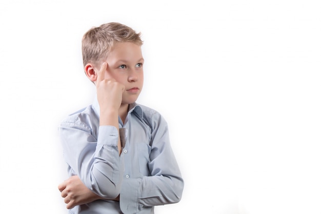 Portrait d'un petit écolier dans une pose pensive isolé sur fond blanc