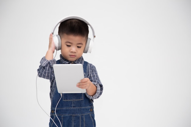 Portrait d'un petit enfant mignon satisfait tenant la tablette et écouter de la musique