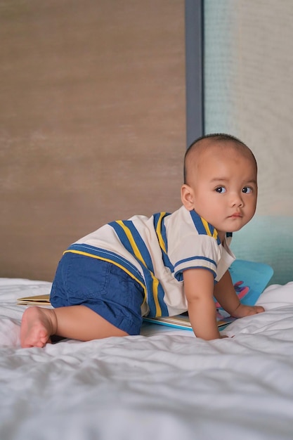 Portrait d'un petit garçon asiatique de 6 mois assis sur le lit à la maison