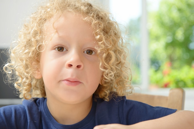 Portrait d'un petit garçon aux cheveux bouclés blonds