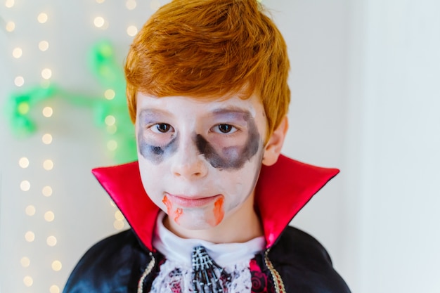 Portrait de petit garçon aux cheveux rouges habillé en vampire effrayant pour Halloween