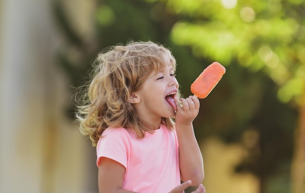 Portrait d'un petit garçon blond mangeant de la crème glacée, des enfants mignons font face à un enfant émotionnel positif