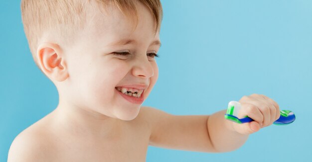 Portrait de petit garçon avec brosse à dents sur bleu.