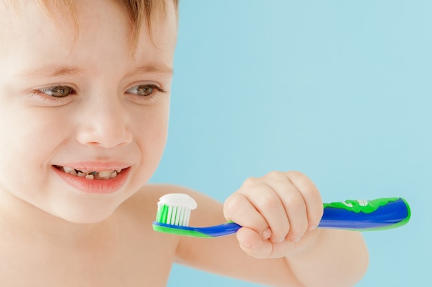Portrait de petit garçon avec brosse à dents sur fond bleu