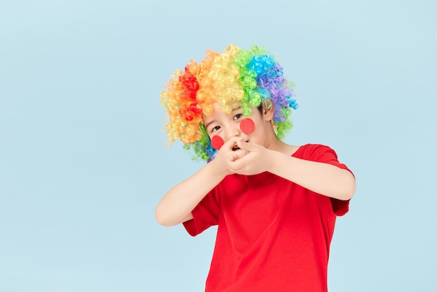 Portrait de petit garçon clown espiègle en perruque rouge