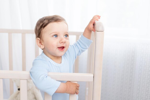 Portrait d'un petit garçon dans un berceau dans une chambre d'enfants avec de grands yeux bleus