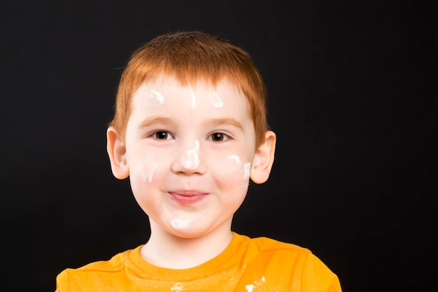 portrait d'un petit garçon dans la cuisine tout en aidant à cuisiner, un garçon aux cheveux roux et aux beaux traits du visage, aidant un enfant dans la cuisine