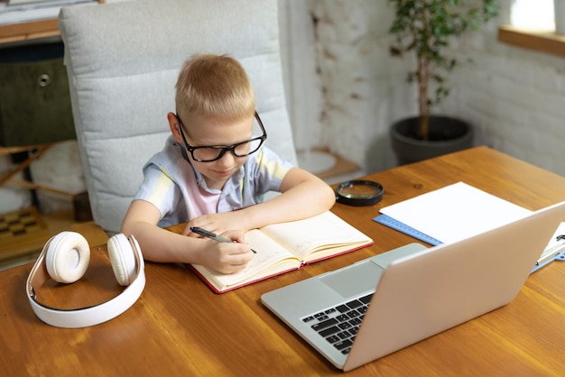 Portrait d'un petit garçon enfant dans des verres étudiant à la maison regardant sur un ordinateur portable travaillant avec un enseignant Éducation en ligne