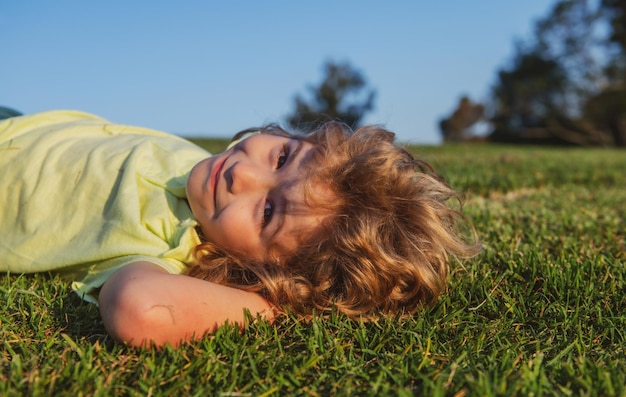 Portrait d'un petit garçon heureux allongé sur l'herbe dans le parc portrait en plein air d'un joli petit garçon