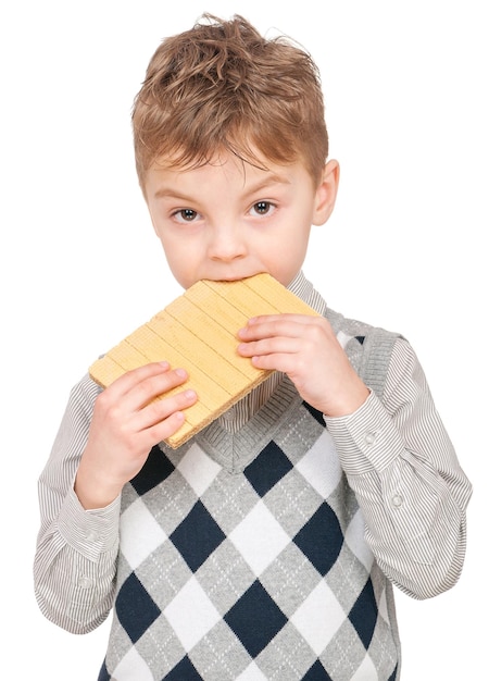 Portrait d'un petit garçon heureux mangeant des gaufres isolé sur un fond blanc Enfant regardant la caméra