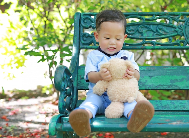 Portrait d'un petit garçon heureux avec ours en peluche dans le jardin.