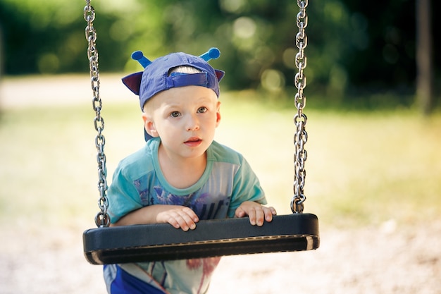 Portrait de petit garçon jouant avec balançoire au parc