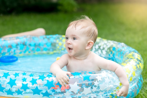 Portrait de petit garçon jouant dans la piscine au jardin