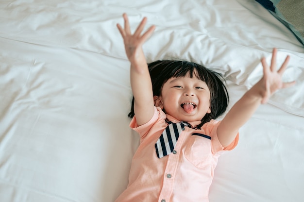 Portrait d'un petit garçon joyeux joyeux dans une chambre blanche Le petit garçon est le bonheur sur le lit