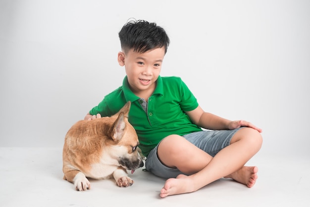 Portrait d'un petit garçon joyeux s'amusant avec chien corgi gallois sur le sol