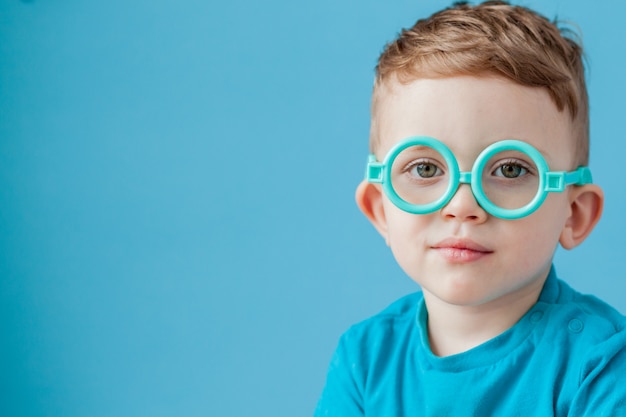 Portrait d'un petit garçon à lunettes jouet sur fond bleu