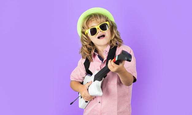 Portrait de petit garçon à lunettes de soleil roses jouant de la guitare électrique Joli enfant garçon chante et joue de la guitare électrique avec des émotions vives