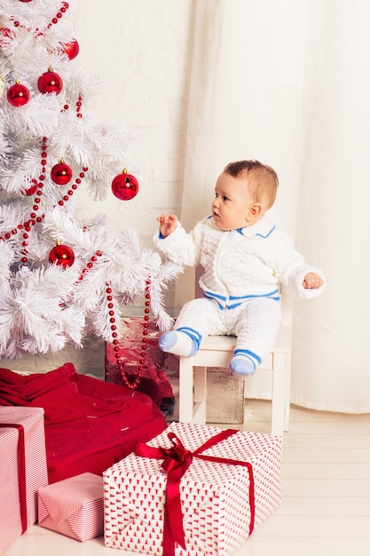 Portrait d'un petit garçon à la maison près de l'arbre de Noël.