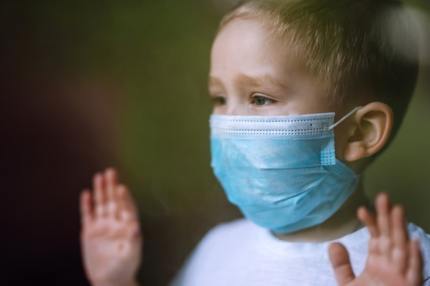 Portrait de petit garçon avec masque médical regardant la caméra dans la ville