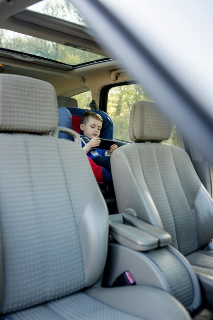 Portrait d'un petit garçon s'ennuie assis dans un siège d'auto