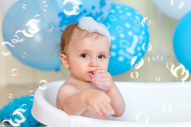 Portrait d'un petit garçon se baignant dans une baignoire avec des ballons et des bulles de savon, bonne enfance, anniversaire des enfants