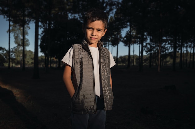 Portrait d'un petit garçon avec ses mains dans ses poches en plein air.